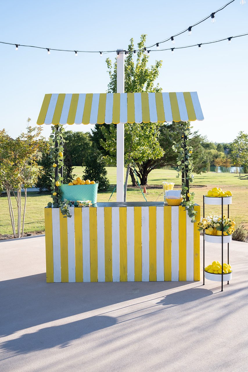 Outdoor empty nostalgic lemonade stand on a lawn with lake and string lights
